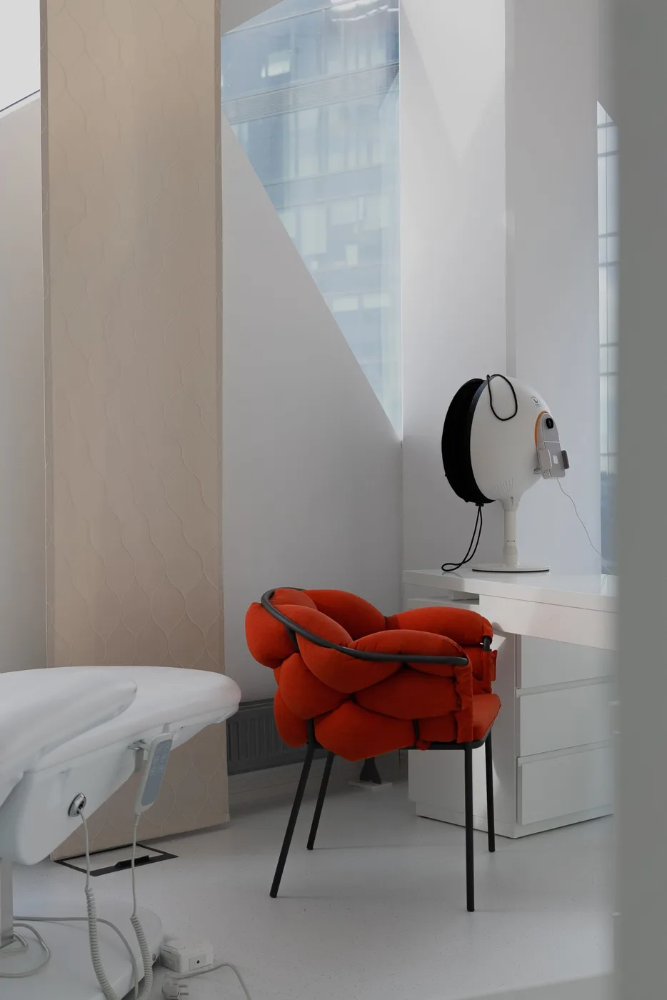 Treatment room with the red armchair and the city behind the glass